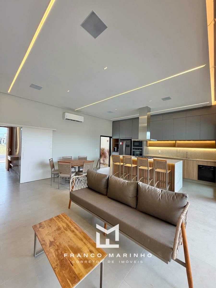 Sala com sofá, mesa de jantar e cozinha com ilha