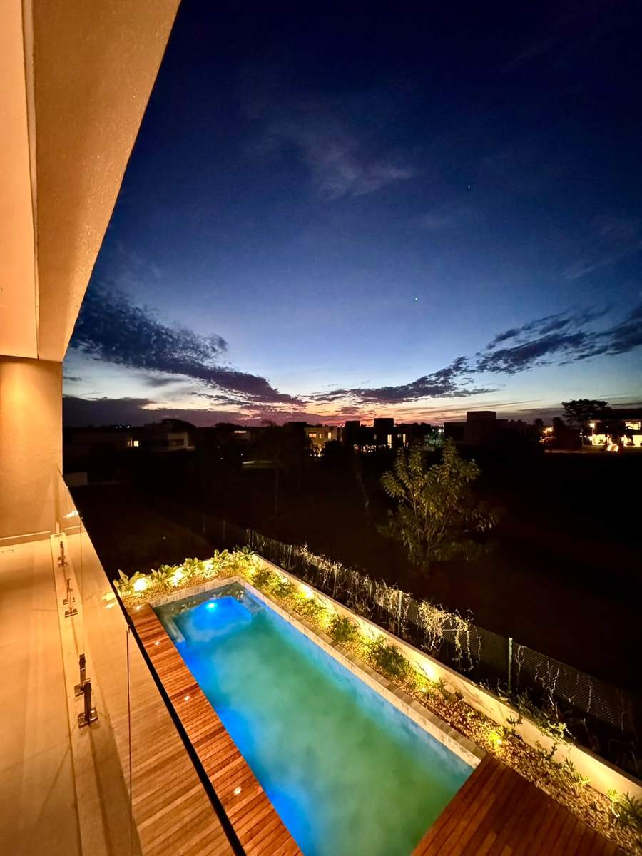 Piscina iluminada vista da varanda da suíte, à noite
